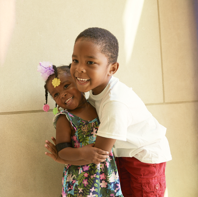 Young Black boy hugging his younger sister