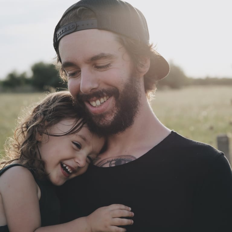 Father Standing in Field Holding Toddler Daughter