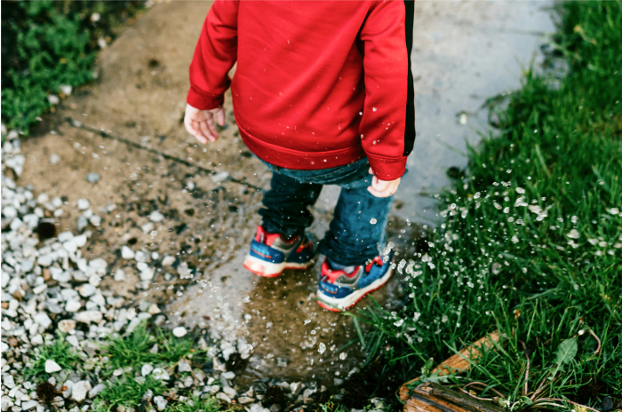 Young child splashing in a puddle