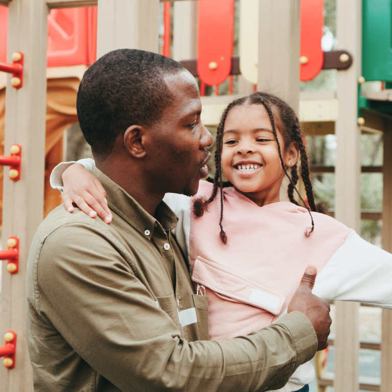 Black Father Holding Smiling Daughter at Playground