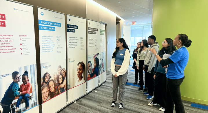 College students looking at PolicyLab portfolio banners at Research Day event