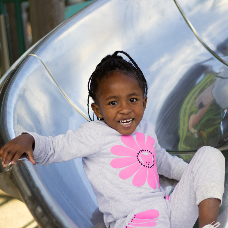 Young Black Girl Smiling on a Playground Sliding Board
