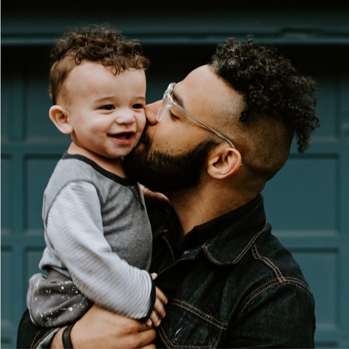 Father Holding Toddler Son and Kissing Cheek