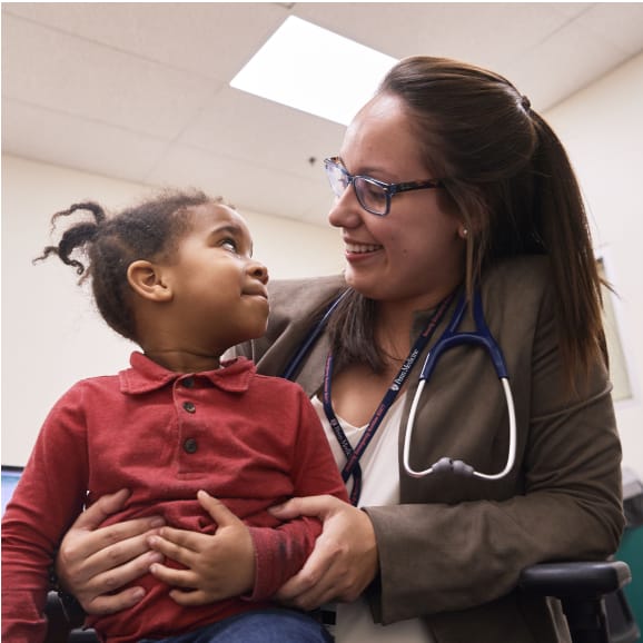 Smiling Woman with Stethoscope Holding Toddler