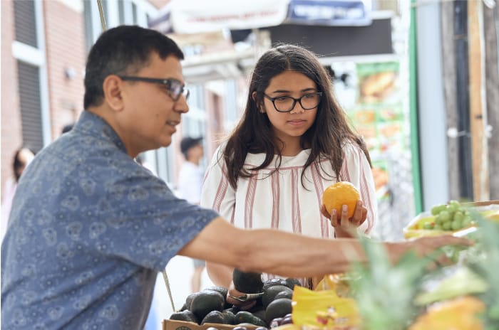 Father and Teen Daughter Looking at Produce at Market