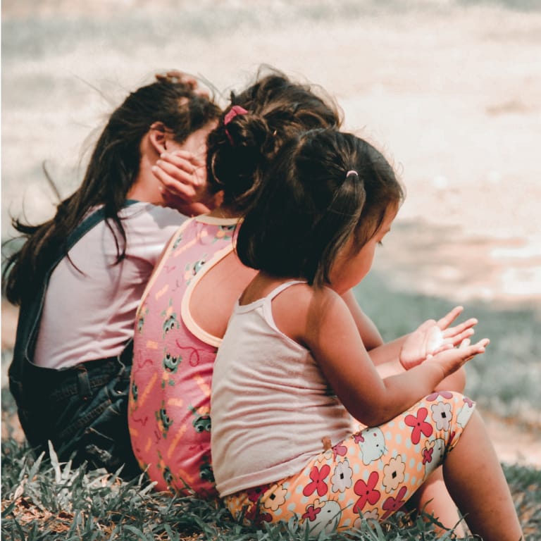 Three Young Girls Sitting Together in Grass