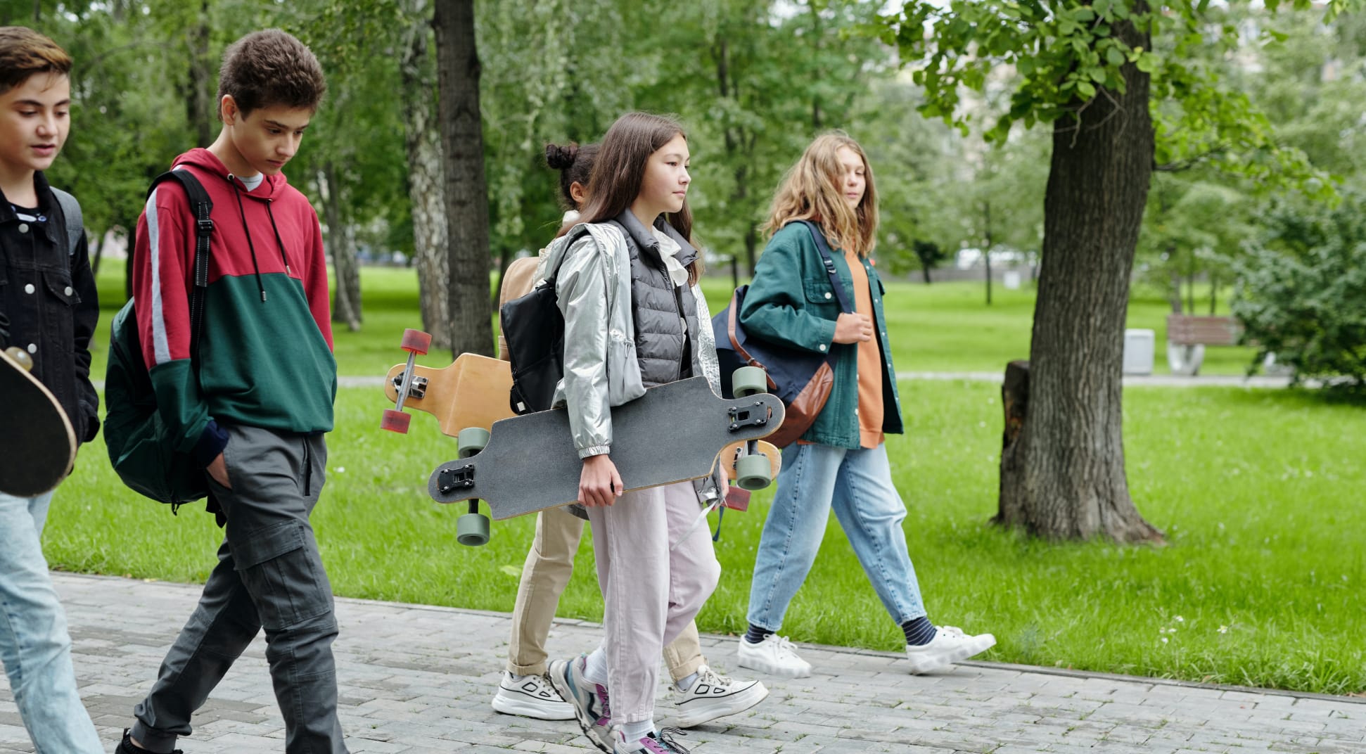 Teenagers Walking Outside Holding Backpacks and Skateboards