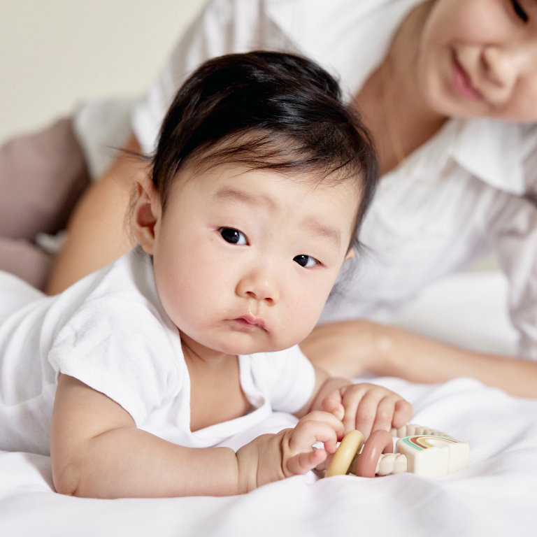 Mother Watching Asian Baby Play with Toy