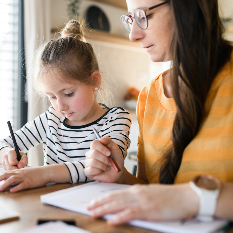 Young White Girl and Woman Sitting at a Table Looking at Notebooks