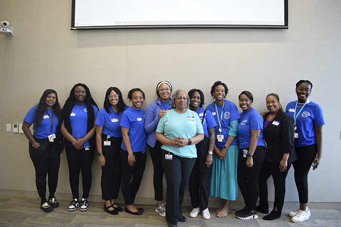 Eleven members of PolicyLab's Visibility and Voice Committee stand in a conference room wearing matching blue shirts. 