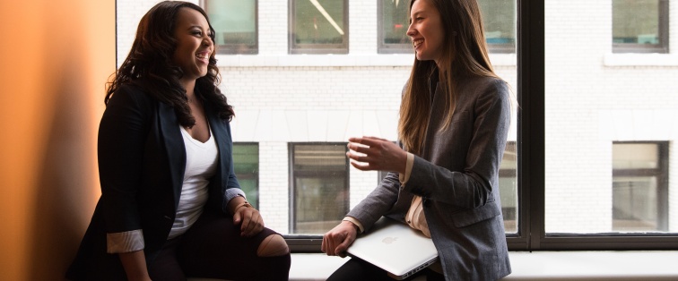 two women speaking and laughing together