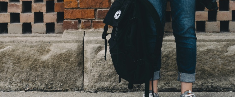 teenager holding a backpack with sneakers on 