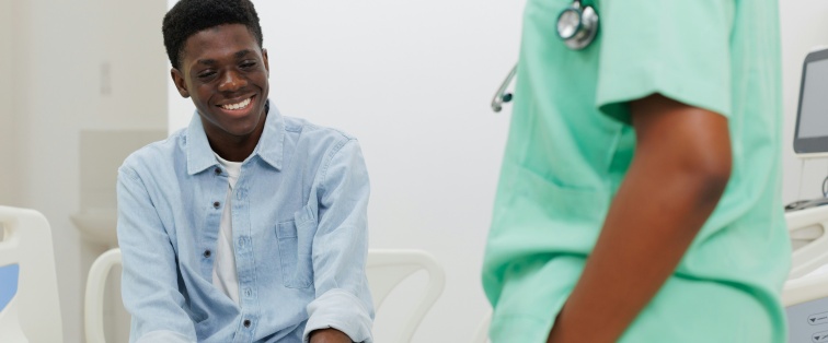 male-presenting youth who is black sitting with medical professional